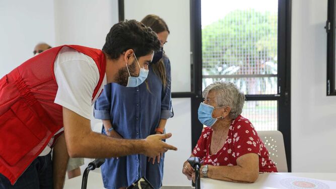 Una mujer mayor habla con uno de los técnicos de Cruz Roja en el centro cívico de La Ardila.