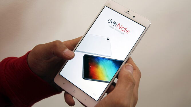 Un usuario revisa un teléfono móvil Xiaomi  en un centro de exposición de productos de la marca en Pekín (China).