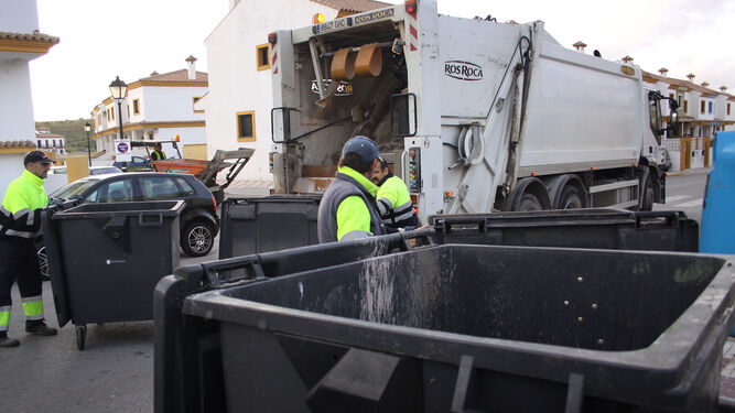 Operarios de Arcgisa recogen la basura en una calle de Los Barrios.