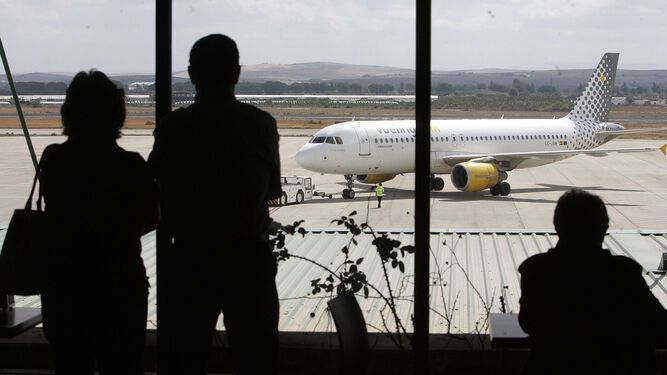 Pasajeros en el aeropuerto de Jerez con un avión de Vueling al fondo.