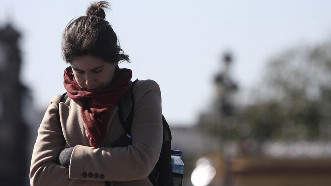 Una joven camina resguardándose del frío en Sevilla.