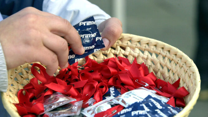 Un reparto de preservativos y lazos rojos en una mesa de concienciación sobre el VIH.