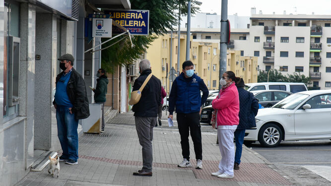 Varias personas hacen cola para acceder a un establecimiento en Algeciras.