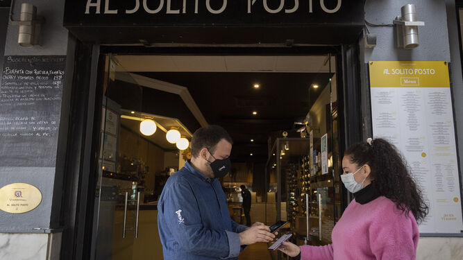 Una mujer muestra su pasaporte Covid para entrar en un restaurante