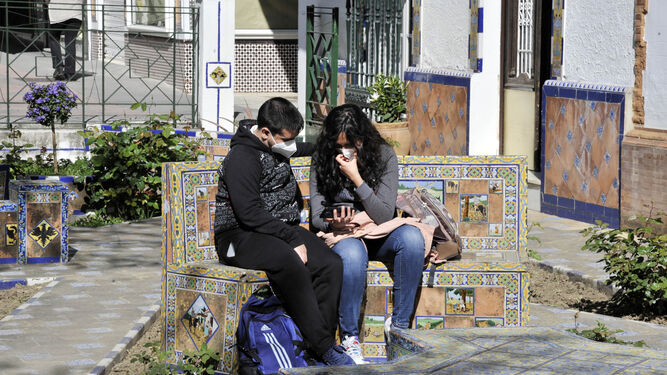 Dos jóvenes consultan sus móviles en una plaza serrana.