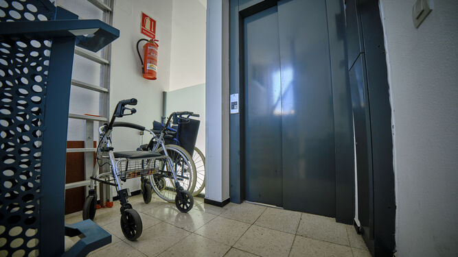 Un andador y una silla de ruedas junto a un ascensor de un edificio de Cádiz.