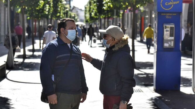 Dos hombres hablan con mascarillas en el centro de Algeciras.