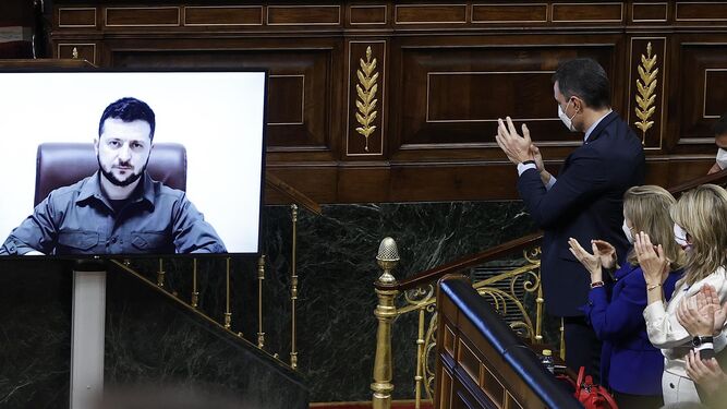 Pedro Sánchez aplaude la intervención por videoconferencia de Volodímir Zelensky en el Congreso de los Diputados.