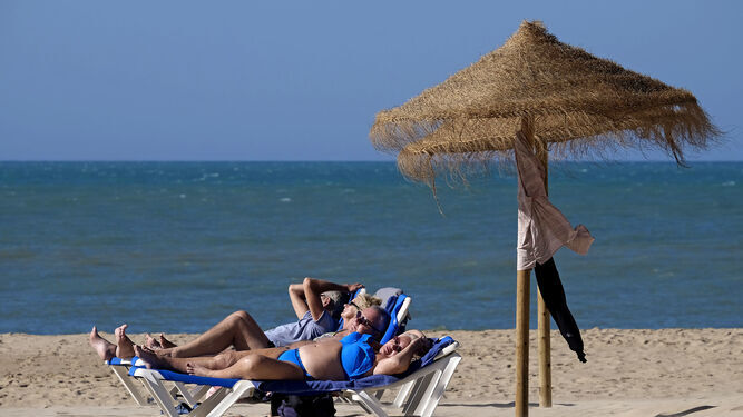 Turistas tomando el sol en la playa de La Victoria de Cádiz.