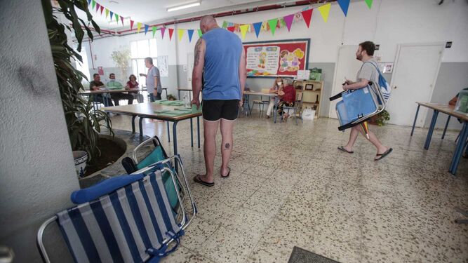 Personas con sillas de playa acuden a votar en un colegio electoral de Cádiz.
