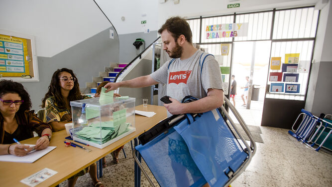 Un hombre acude a votar en un colegio electoral de Cádiz con su silla de playa a cuesta.