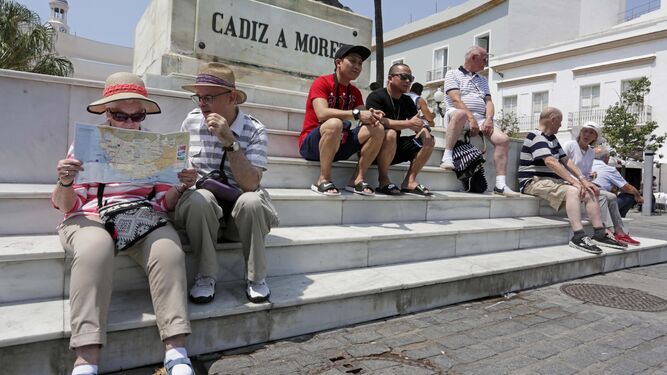 Varios turistas, sentados bajo el monumento a Moret, en Cádiz.