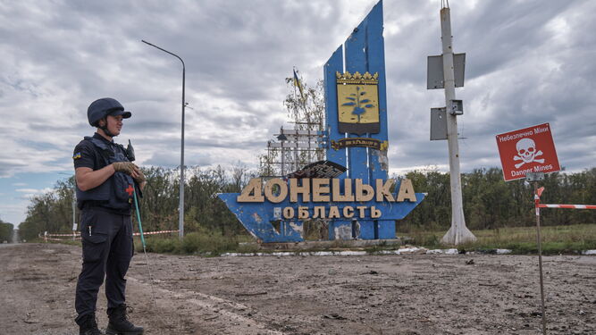 Un zapador ucraniano permanece en guardia junto a un cartel que avisa del peligro de minas en la simbólica frontera entre las regiones de  Jarkov y Donetsk.