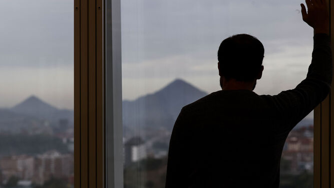 Un hombre mira por la ventana de su oficina durante un descanso de su jornada laboral.