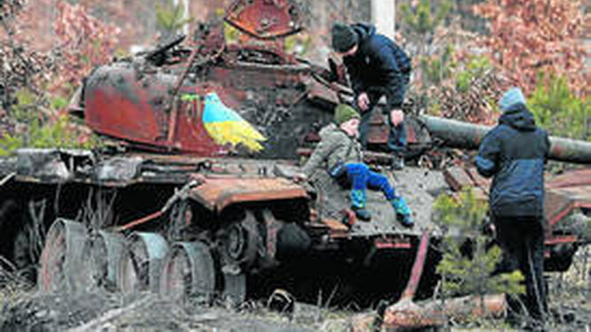 Unos niños ucranianos juegan en los restos de un tanque ruso cerca de Kiev.