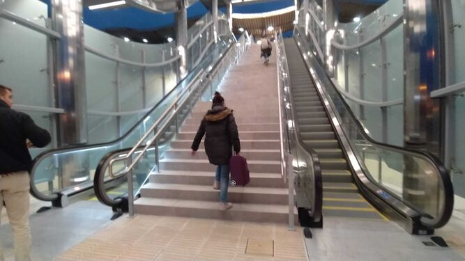 Una usuaria con su maleta sube a pie a la estación de Bahía Sur al no funcionar la escalera mecánica cuatro días después de su inauguración.
