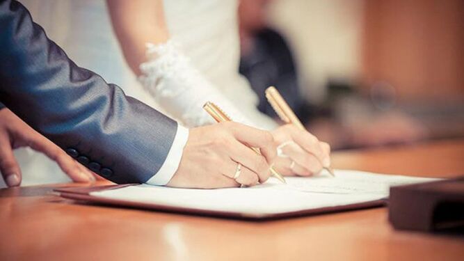 Una pareja firma los documentos el día de su boda