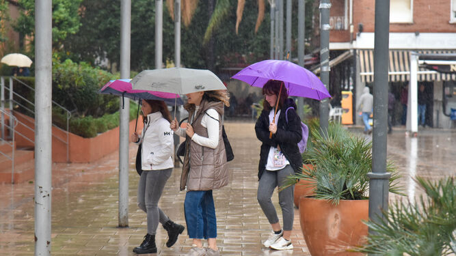 Tres personas bajo la lluvia, en Algeciras.