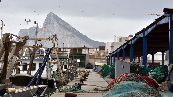 Pesqueros en el puerto de La Atunara y, al fondo, la silueta del peñón de Gibraltar.