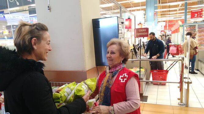 Una clienta de Alcampo entrega alimentos a una voluntaria de Cruz Roja durante una de sus campañas.