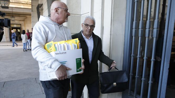 José Luis Escañuela, expresidente de la RFET (a la derecha), entra este martes en la Audiencia de Sevilla con una voluminosa documentación.